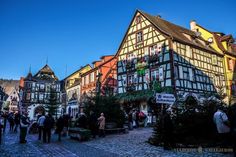 people are walking around in front of some old buildings on a cobblestone street