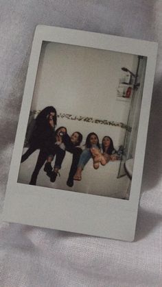 a polaroid photo of four women hanging out in a bathroom with one holding a baby