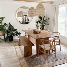 a dining room table with chairs and a bench in front of a mirror on the wall