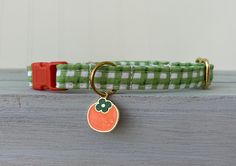 a green and white checkered dog collar with a gold plated charm on it