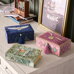 three decorative boxes sitting on top of a wooden table next to a framed photograph and a clock