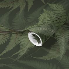 a green leafy wallpaper with a white circular object on it's side