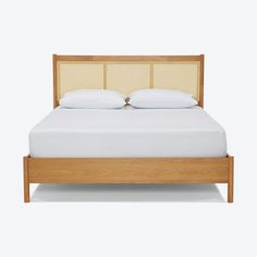 a bed with two pillows on top of it and a headboard made out of wood