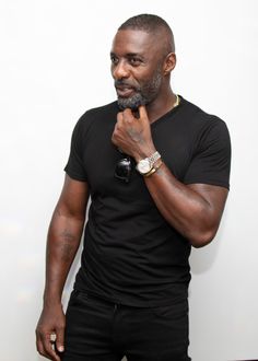 a man standing in front of a white wall with his hand on his chin and looking at the camera