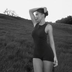 a black and white photo of a woman in a field with her hand on her head