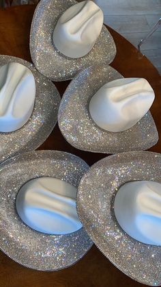 four shiny silver plates sitting on top of a wooden table next to white napkins