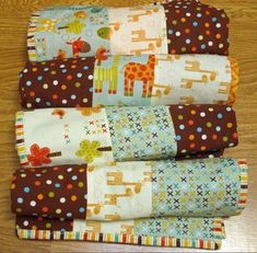 four baby quilts stacked on top of each other with giraffes and dots