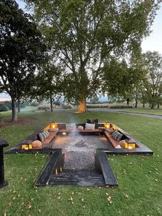 a fire pit in the middle of a grassy area with candles lit up on it