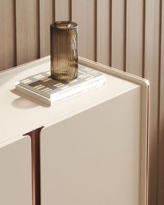 a glass vase sitting on top of a white cabinet next to a book and magazine