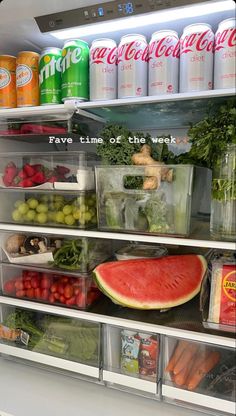 an open refrigerator filled with lots of fresh fruits and vegetables next to cans of soda