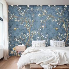 a bed sitting under a blue wall next to a wooden table with two lamps on it