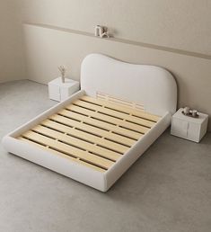 a white bed with wooden slats on the bottom and headboard is next to two nightstands