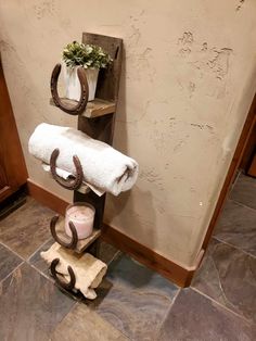 a towel rack with two horseshoes on it next to a candle and some flowers