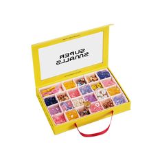 a yellow box filled with lots of different types of candies on top of a white surface