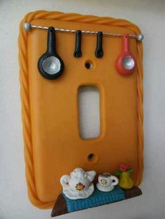 an orange switch plate with kitchen utensils hanging on it's side,