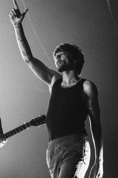 black and white photograph of a man holding an electric guitar in the air with his right hand up