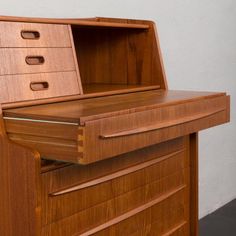 a wooden desk with drawers on the top and one drawer open to show its contents