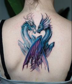 the back of a woman's shoulder with a blue and purple dragon tattoo on it