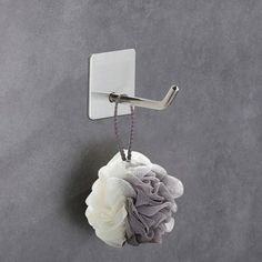 a white flower hanging from a hook on a gray wall next to a towel rack