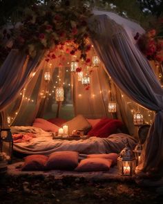 a bed covered in lots of pillows under a canopy with lights hanging from the ceiling