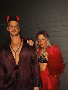 two people dressed in devil costumes standing next to each other and posing for the camera