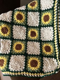 a crocheted granny blanket with sunflowers on the front and sides, sitting on a chair