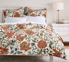 a bed with an orange and white floral comforter