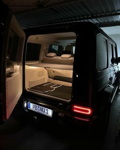 the back end of a van with its doors open in a dark garage, filled with furniture