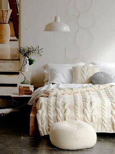 four candles are lit on the wall above a bed with white blankets and throw pillows