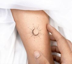 a person with a small sun tattoo on their arm