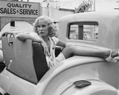 a woman sitting on the back of an old car