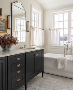a bathroom with a tub, sink and large mirror in it's center area