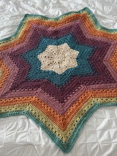 a crocheted blanket is laying on a bed