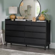 a dresser with a mirror and vases on it in front of a blue wall