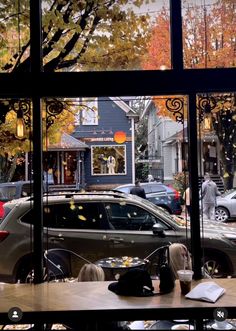 people sitting at a table in front of a window with cars parked on the street