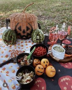 a table topped with lots of food on top of a picnic blanket next to watermelon