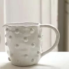 two white mugs sitting next to each other on top of a table with polka dot designs