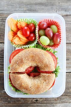 a plastic container filled with a sandwich and fruit