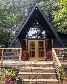 a - frame cabin in the woods with stairs leading up to it's front door