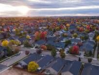 an aerial view of a neighborhood with houses and trees in the foreground at sunset