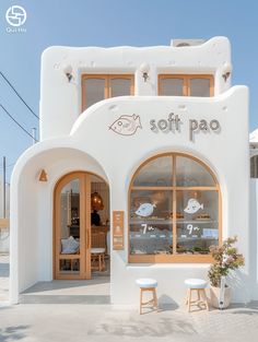 a white building with two stools in front of it and the words soft pao written on the window