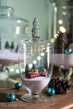 a glass jar filled with snow sitting on top of a table next to christmas decorations