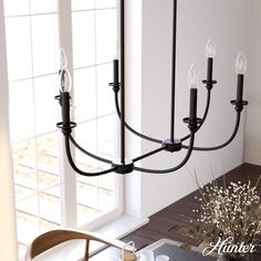 a black chandelier hangs over a dining room table with flowers in the center