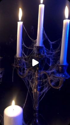 a group of lit candles sitting on top of a metal candelabra covered in spider web