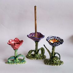 three colorful glass vases sitting next to each other on top of a white surface