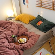 an unmade bed with food and drinks on the table in front of it,