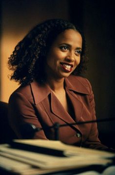 a woman sitting at a table with a microphone in front of her, smiling for the camera