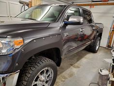 a gray truck parked in a garage next to a wall with tools on it's sides