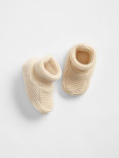 a pair of knitted baby shoes sitting on top of a white surface