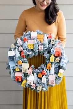 a woman holding a wreath with houses on it